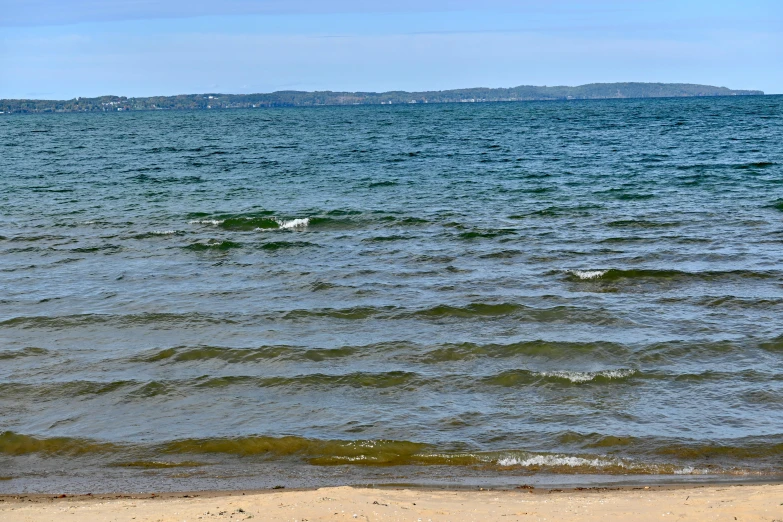 a lone man sitting on the shore of the ocean