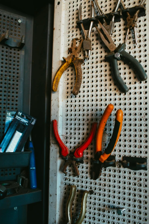 the pliers are on the pegboard and hanging from the wall