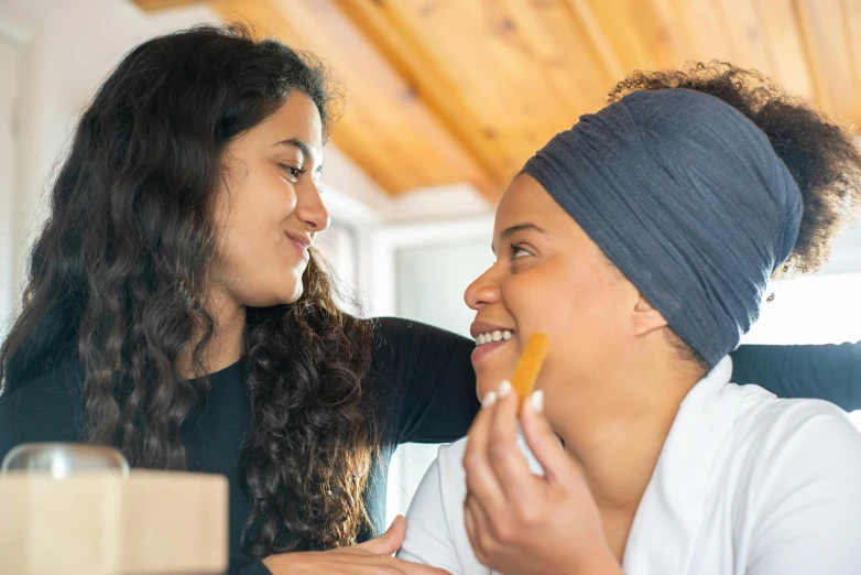 two women are laughing as one eats food