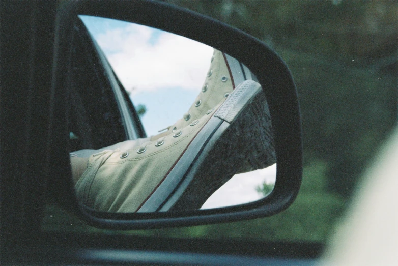 the reflection of someones foot in a car's rear view mirror