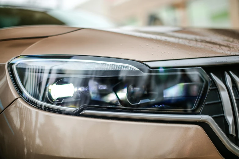 a light brown sports car with its headlights on