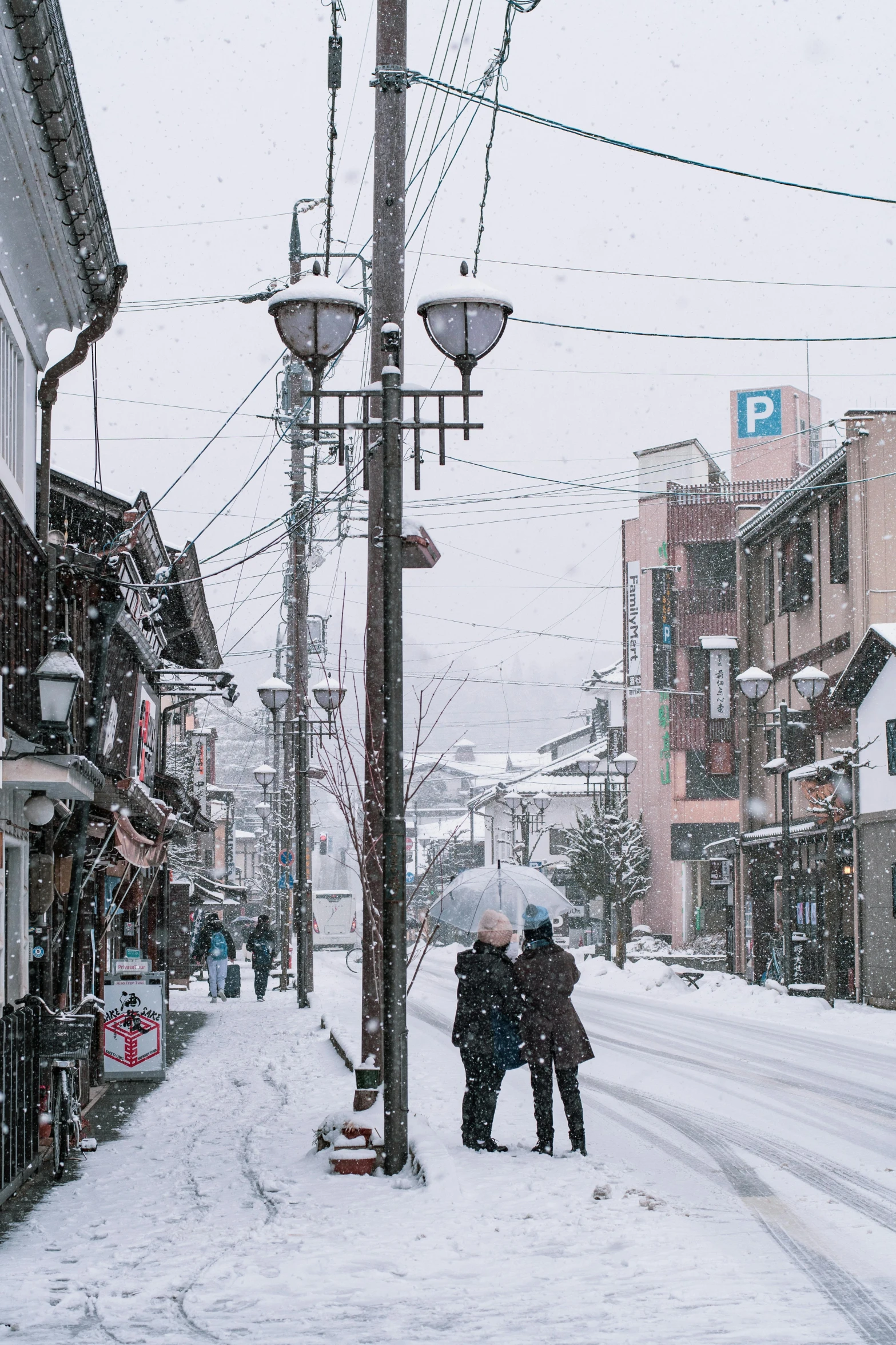 two people walking down a snowy street holding umbrellas