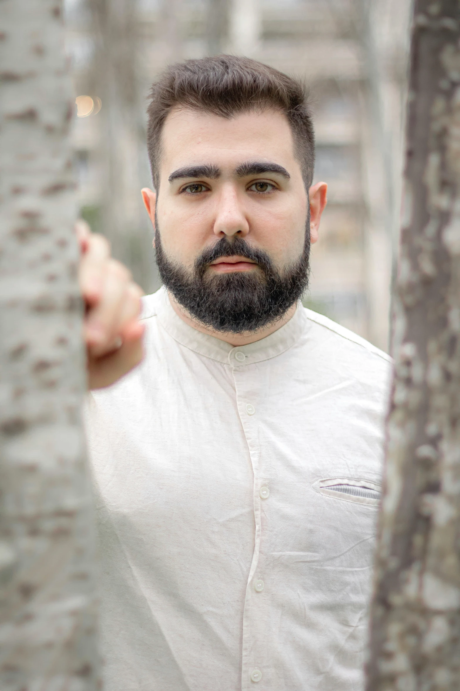 man standing with finger touching tree looking straight ahead