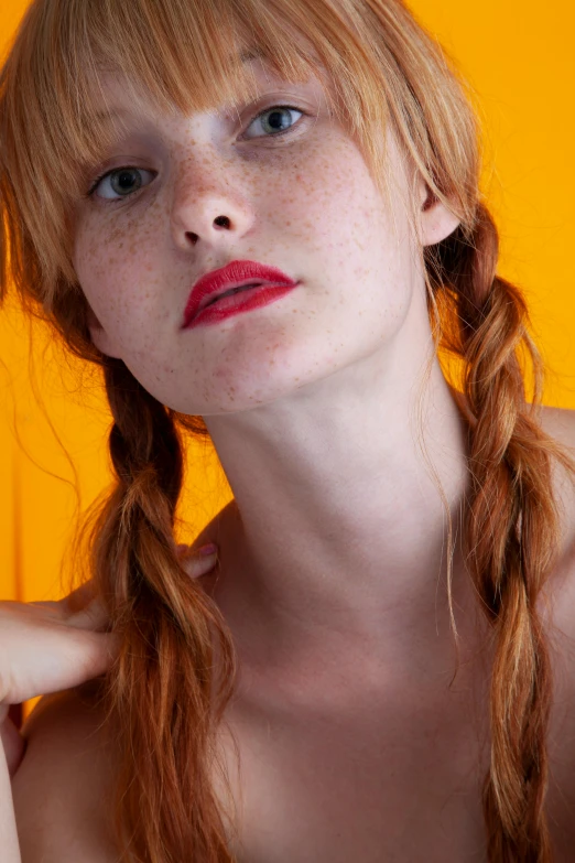 woman with red hair, freckled top and id in front of orange background