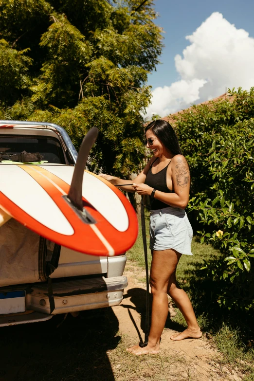 woman holding surfboard by the back of car