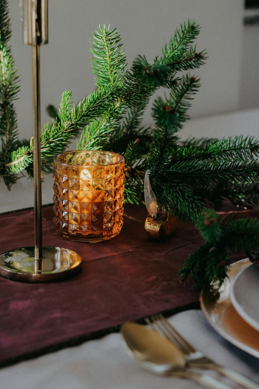 a green christmas tree sits in a vase next to some gold dishes