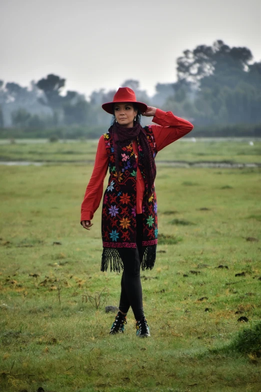 a woman is standing in a field with her hat on