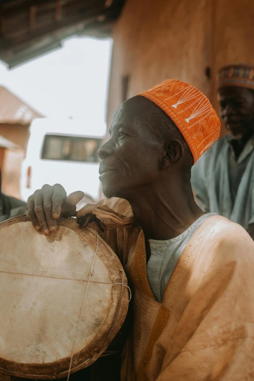 man wearing a colorful headgear and holding a wooden drum