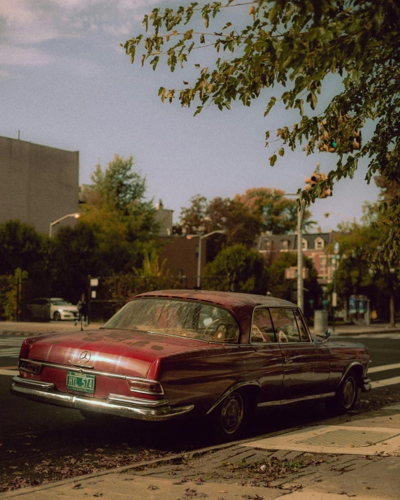 a classic car parked on the side of a road next to a crosswalk