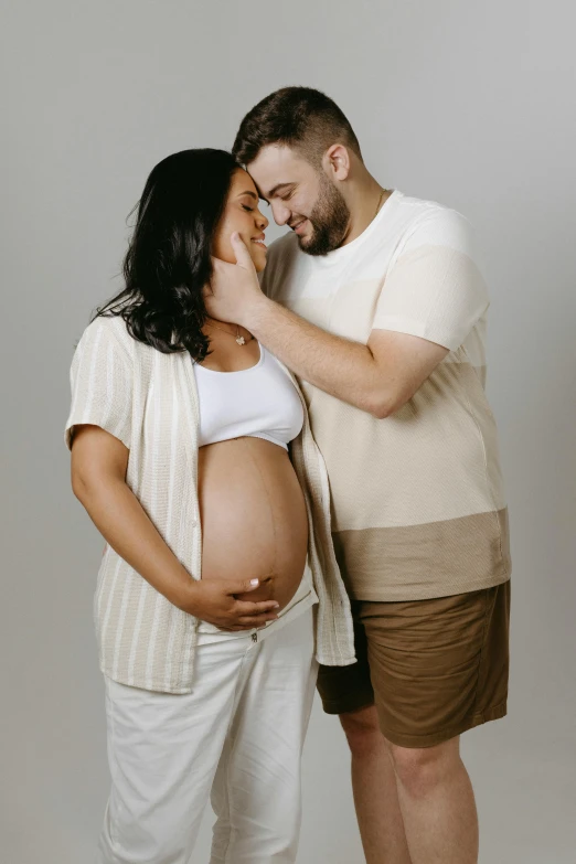 the young couple has their pregnant belly exposed as they pose for this picture