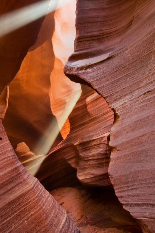 a bright sun beams through an eroded rock