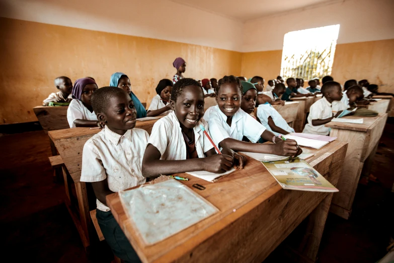 school children are sitting at their desks while taking their notes