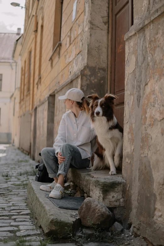 the woman sits on the stone steps with her dog