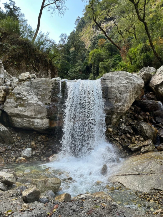 small waterfall next to rocks and trees