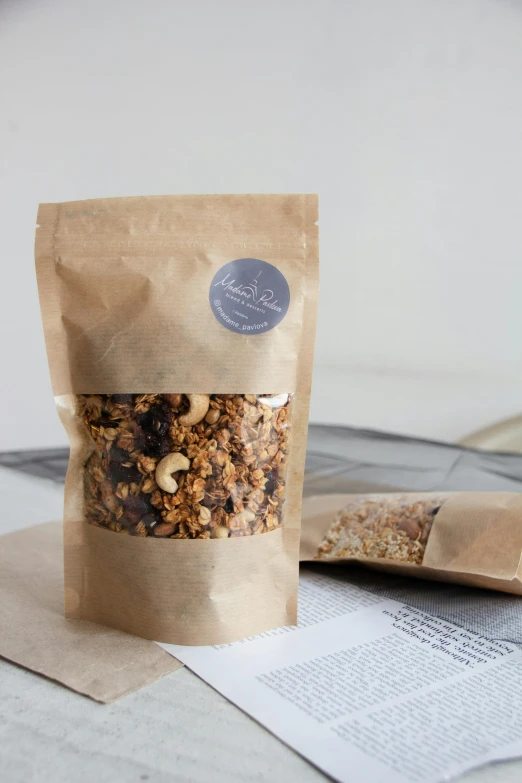two packets of dried granola in paper bags next to a bag of rolled paper