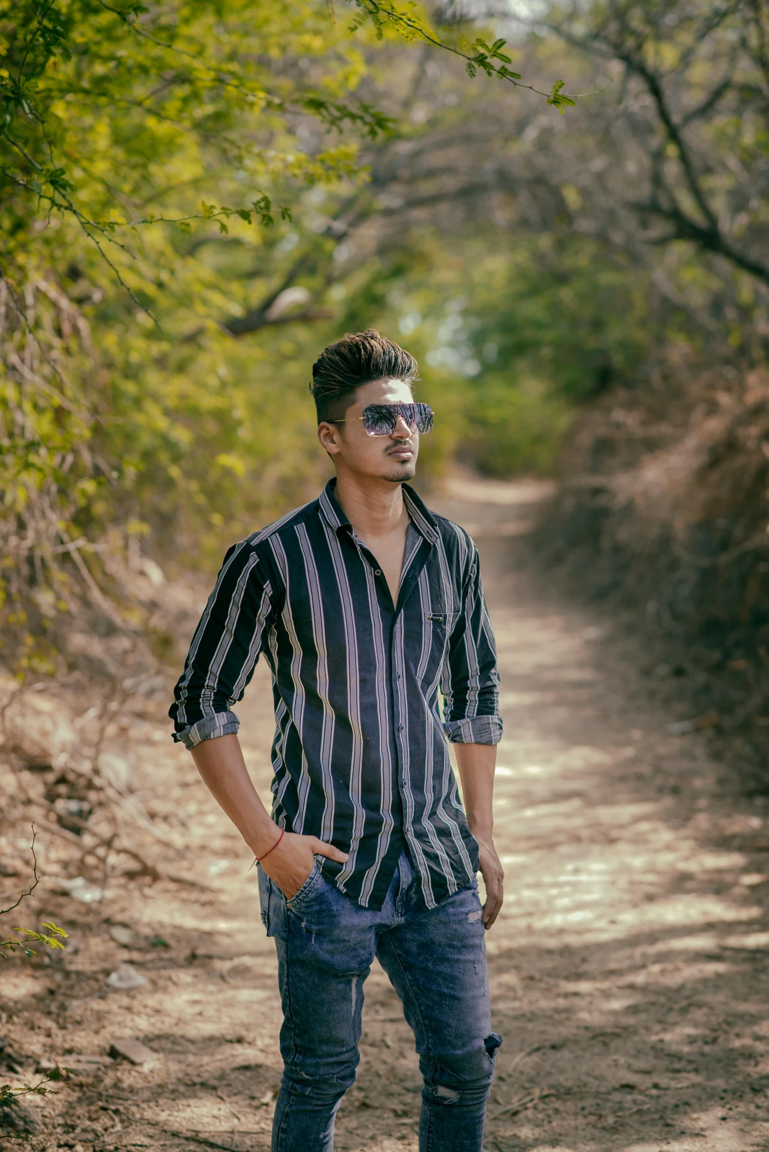 young male wearing sunglasses standing on dirt road