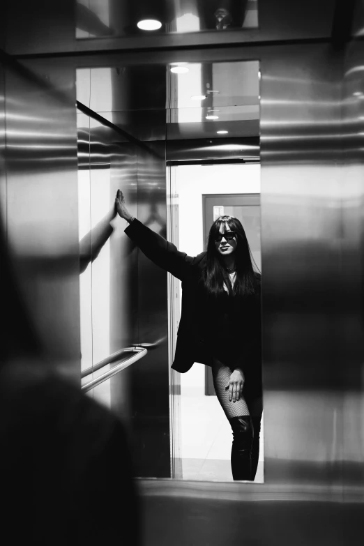 a woman is in an elevator standing next to a mirror