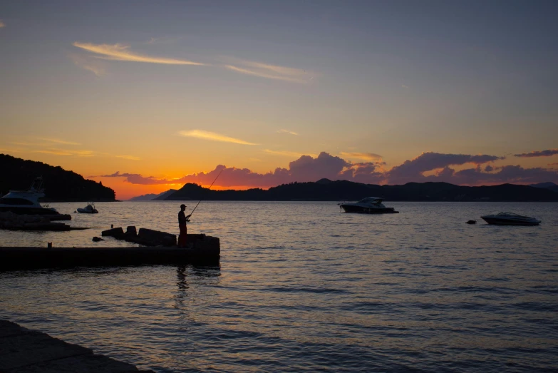 there is a man standing on a dock at sunset