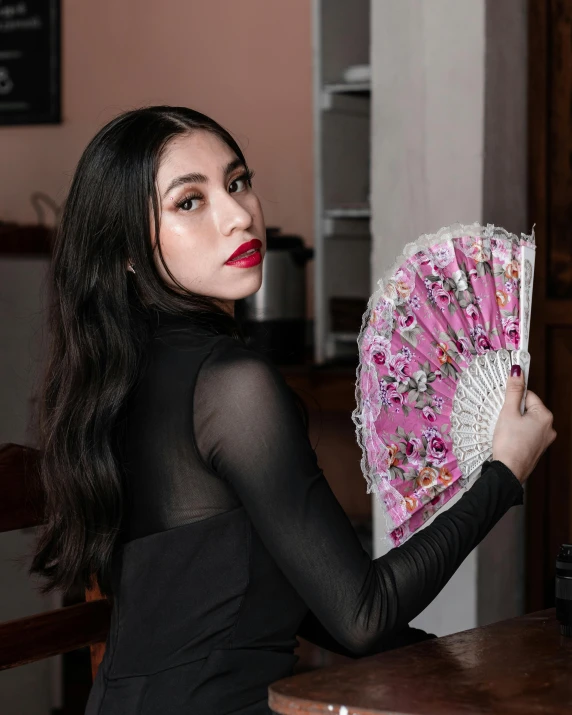 a beautiful woman posing with a pink flower print fan