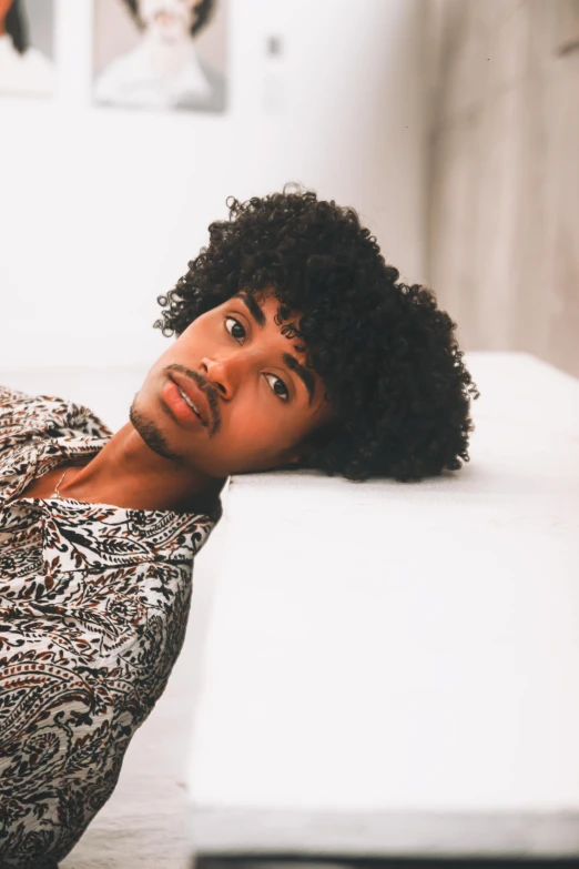 a young man lays on his side on top of a mattress