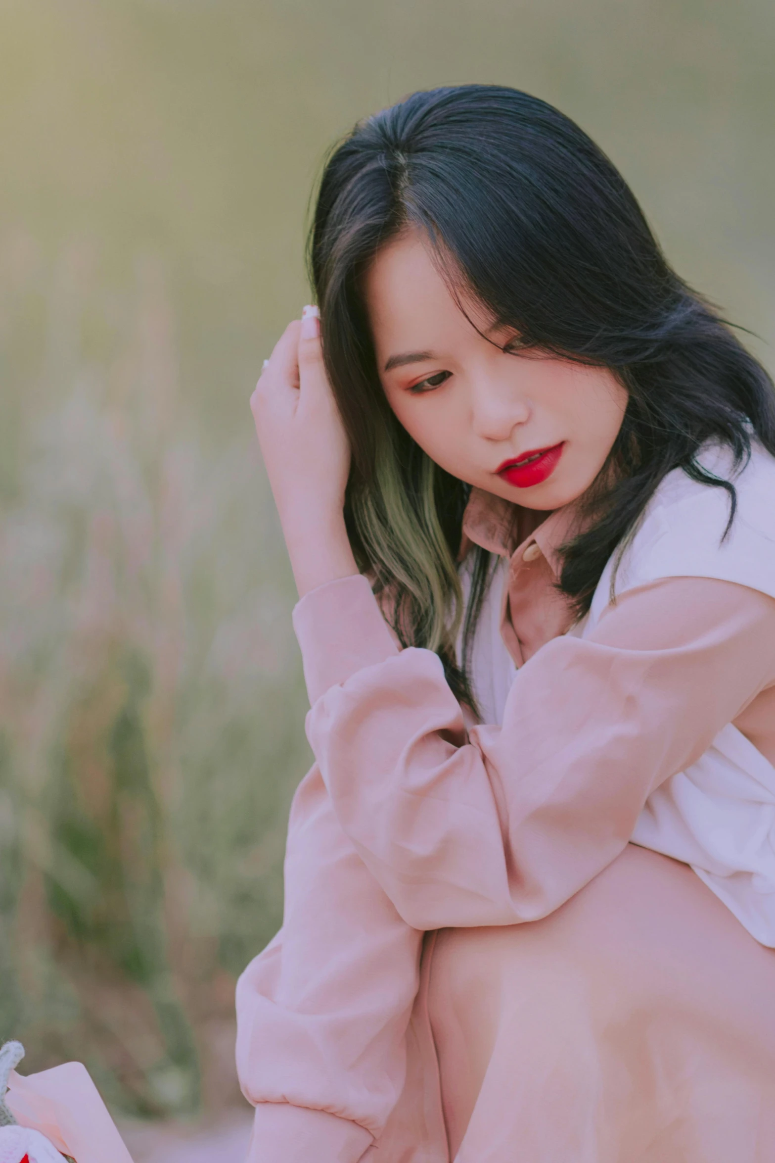 a beautiful young woman sitting in a field