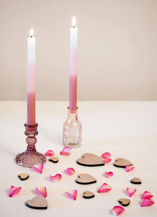 a pink candle next to small hearts