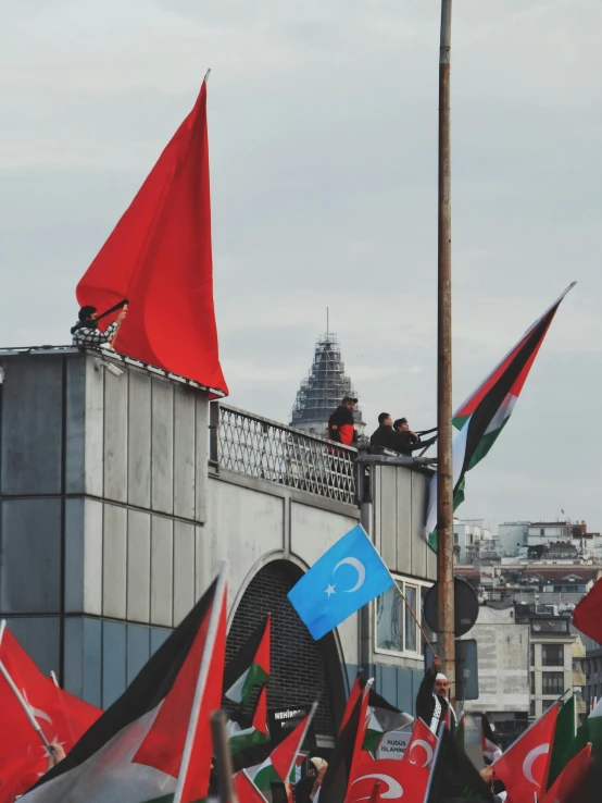 a group of people on top of a bridge with red flags