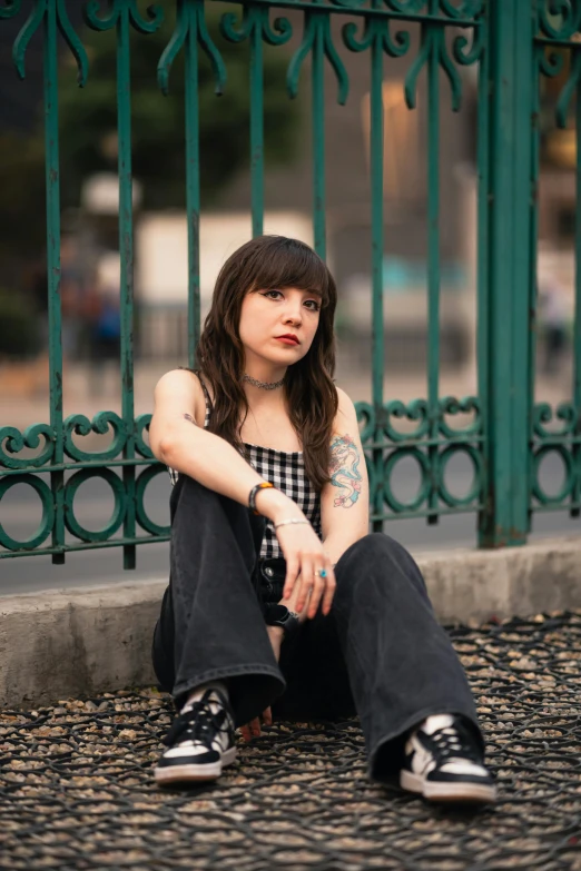 a woman sitting next to a green fence