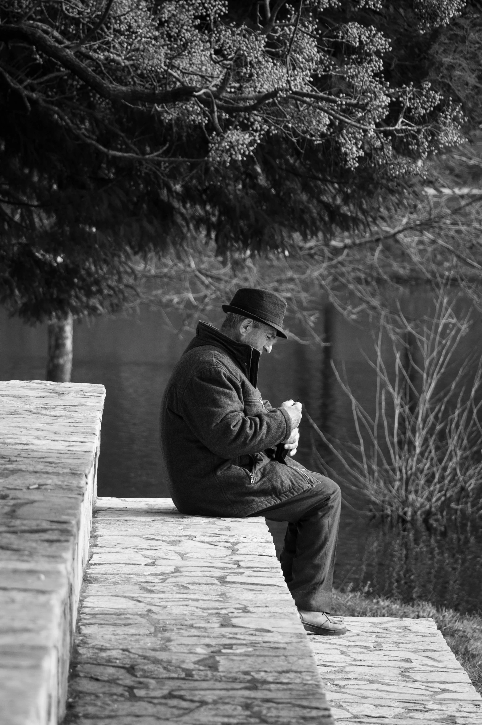 a man in a hat sitting on a bench and smoking