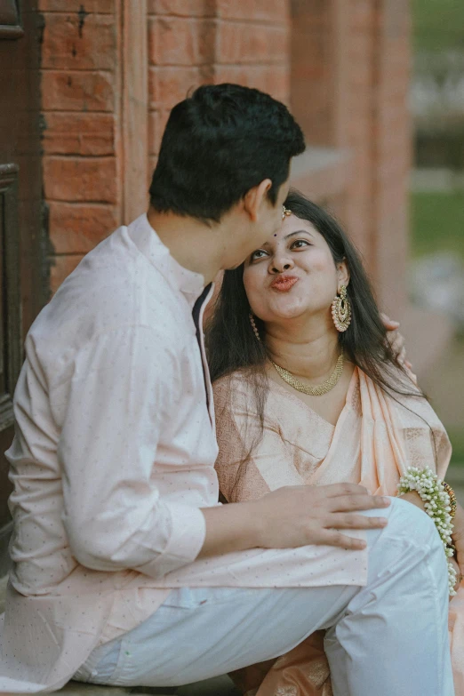 a woman sitting next to a man who is touching his face