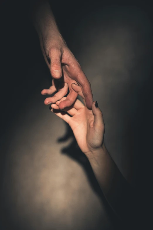 two people's hands reaching together in the dark