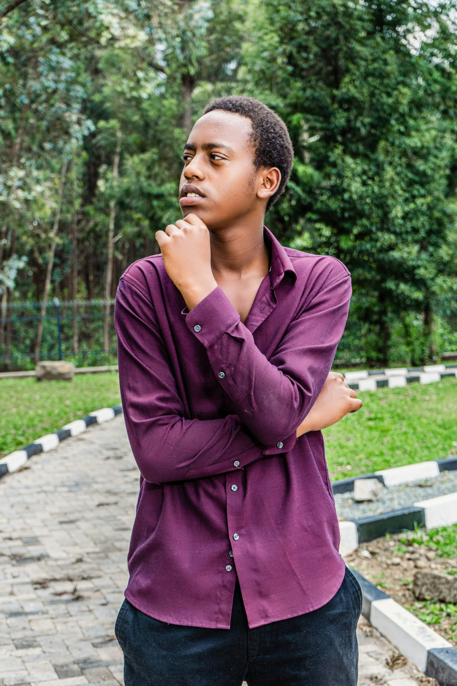 man in purple shirt standing with hands folded on the outside of his face