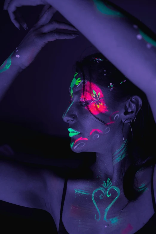 girl with dark body and neon makeup holding her hair back