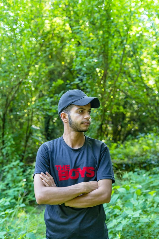 the man is standing in the woods wearing a hat