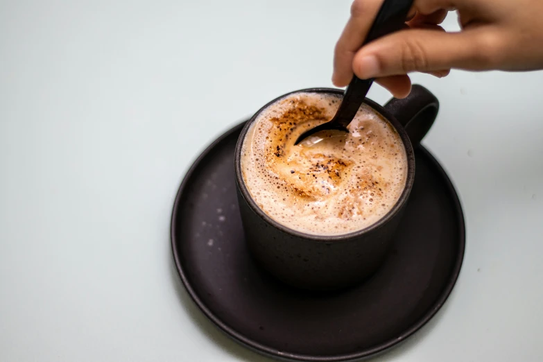 a person is stirring the drink in a cup