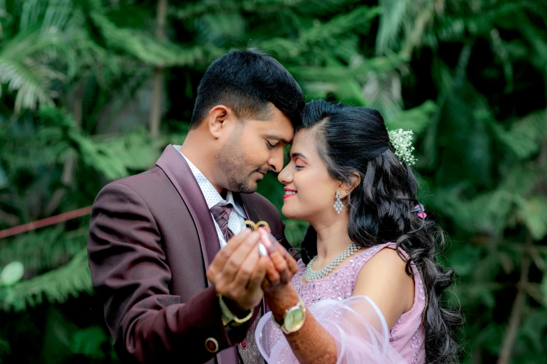 a bride and groom stand together in front of pine trees