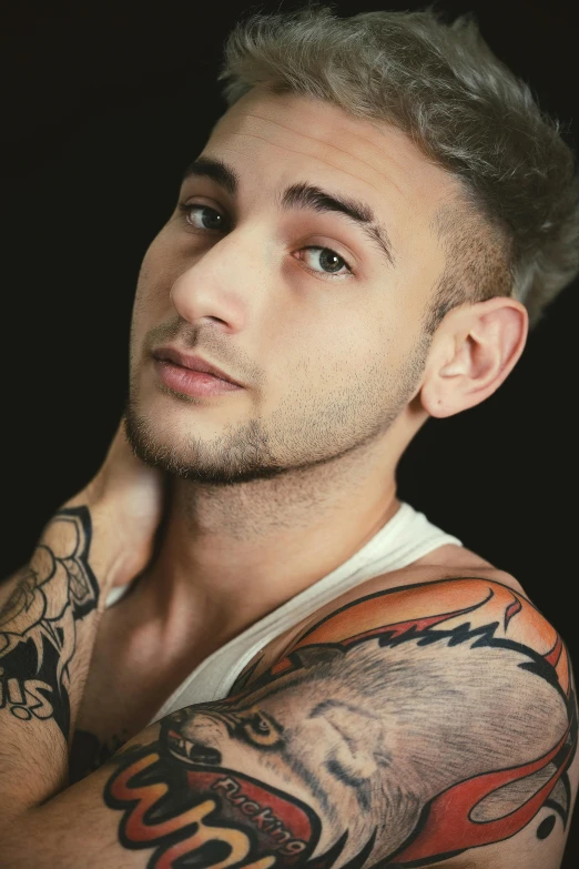 a young man with tattoos on his arms looking to the left