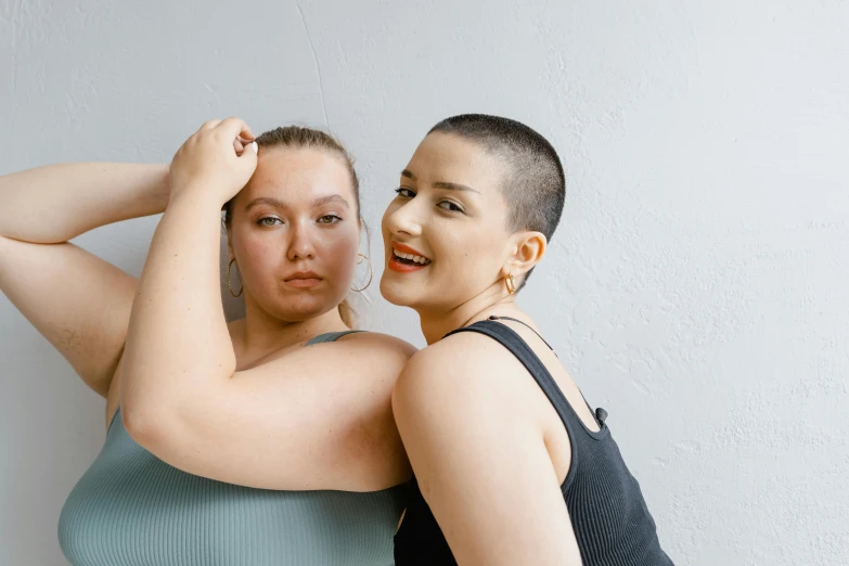 two women pose for a picture against a wall