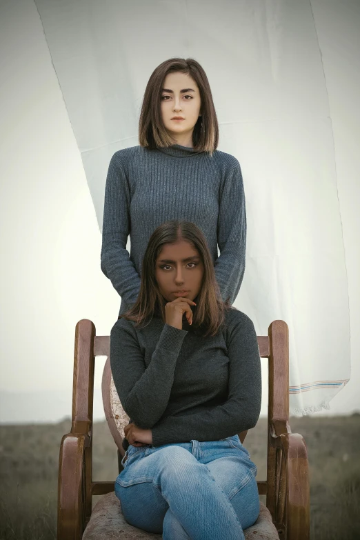 two women that are sitting in a wooden chair