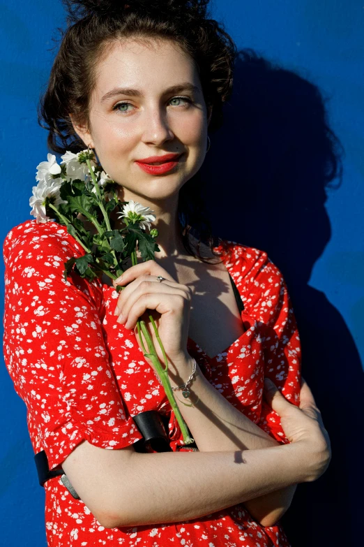 woman holding a flower bouquet against a blue backdrop