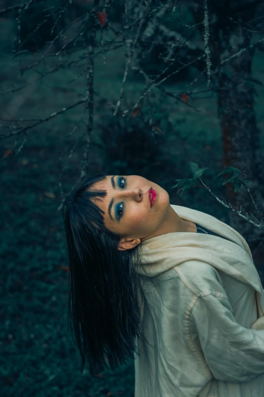 a woman wearing red and black makeup standing in the woods