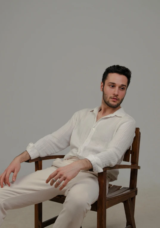 man sitting in wooden chair wearing white shirt