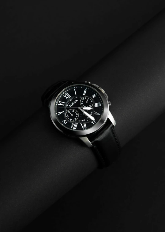 a black watch sitting on top of a leather strap