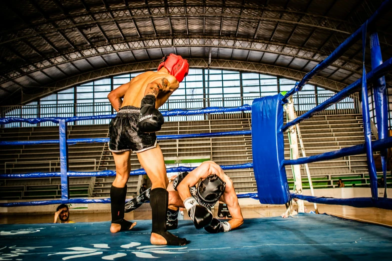 one man is seen standing on the ground, while another man in knee pads and wrestling gloves looks on