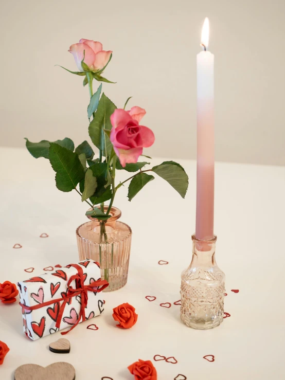 a single candle and some hearts on a table