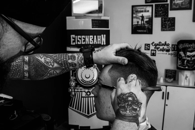 a man getting a haircut with tattoos on his arm and shoulder
