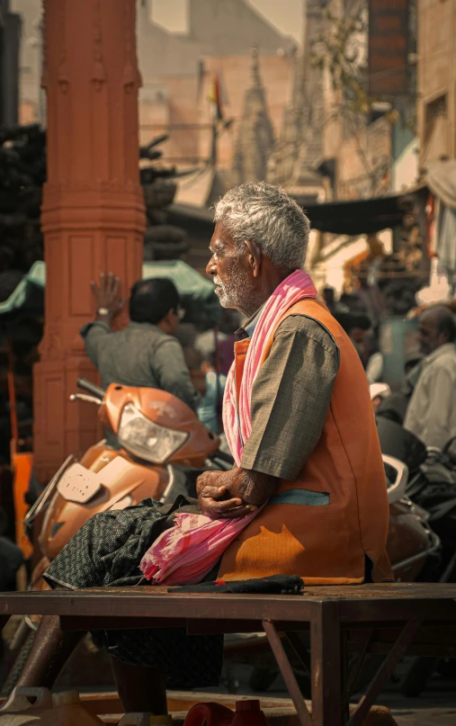 an old man sitting on a wooden bench in a street market