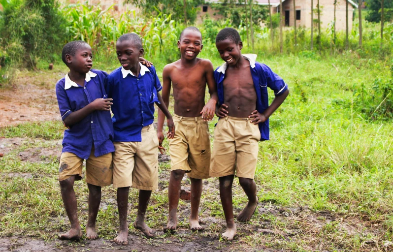 four boys are standing together in the grass