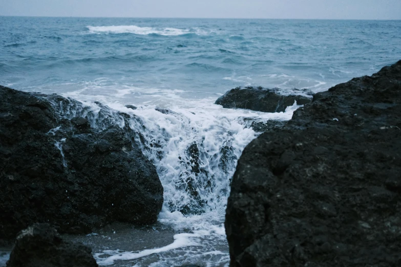 water coming out from a  in the rocks next to the ocean