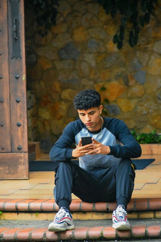 young man sitting on steps looking at cell phone